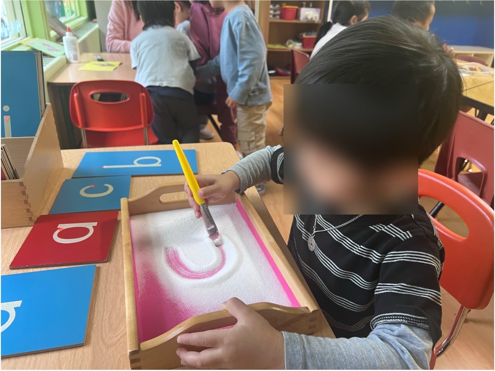 Child tracing sandpaper letters in Montessori activity